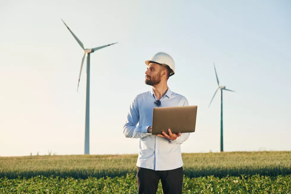 with-laptop-hands-service-engineer-is-field-with-windmills