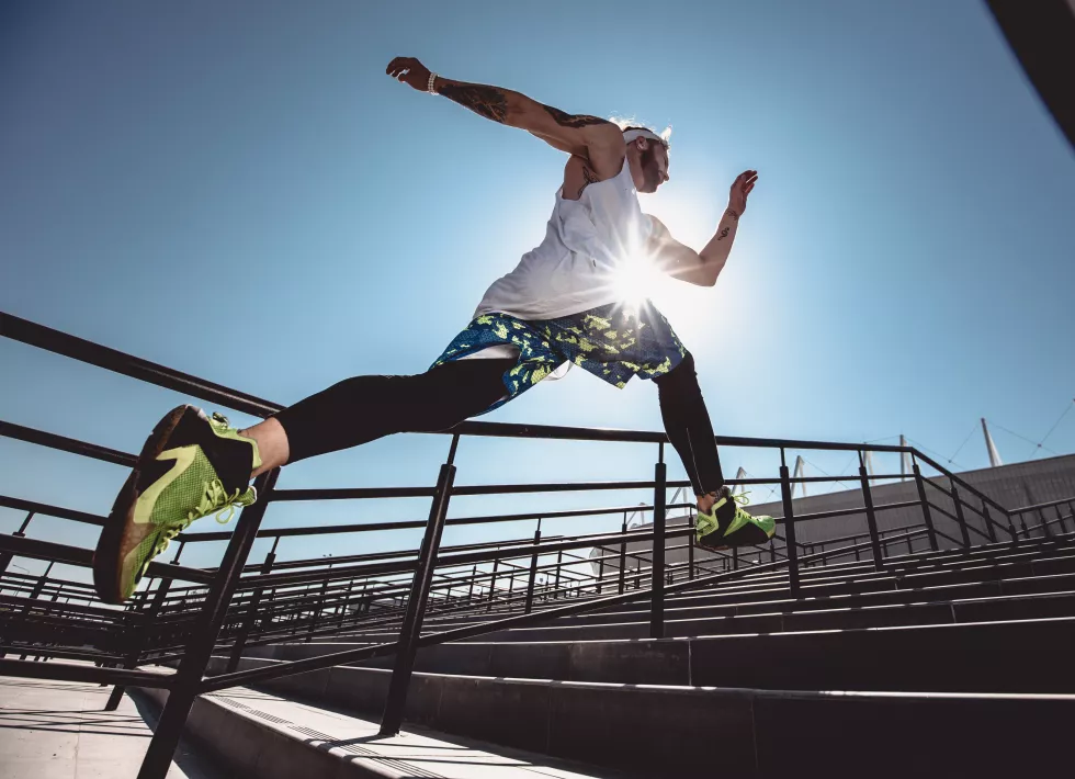 handsome-young-muscular-man-modern-sport-clothing-run-up-stairs-outdoor-bright-sunny-day-wide-angle-photo-jogging-man-sport-lifestyle