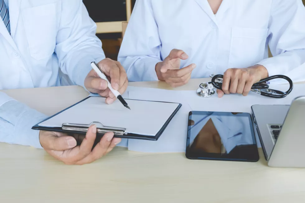two-doctors-have-discussion-sitting-desk-hospital