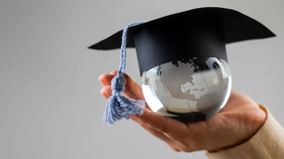 cropped-hand-woman-holding-mortarboard-against-white-background