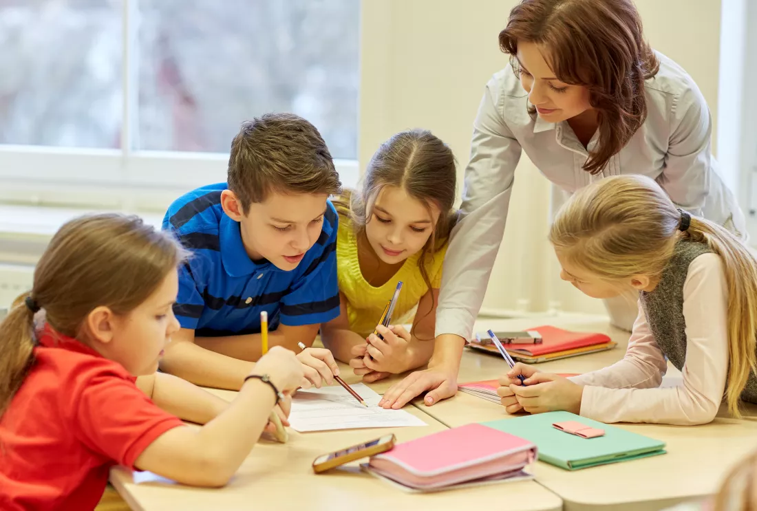 education-elementary-school-learning-people-concept-teacher-helping-school-kids-writing-test-classroom