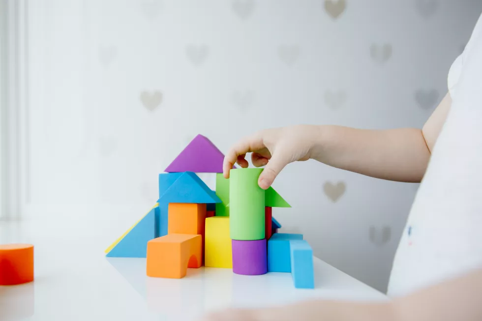 child-hands-playing-with-colorful-wooden-bricks-white-tab