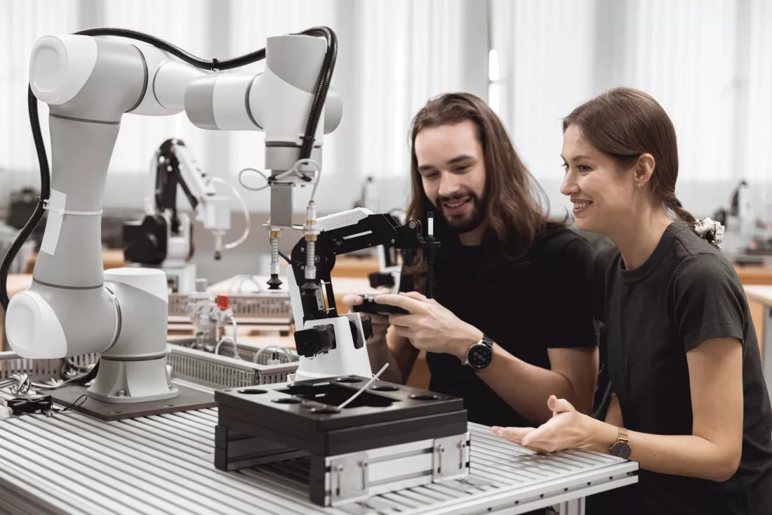 Studenci kalibrują ramię robota przemysłowego w laboratorium robotyki.