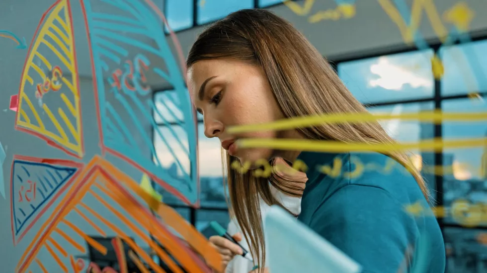 smart-businesswoman-drawing-graph-while-looking-plan-glass-wall-tracery