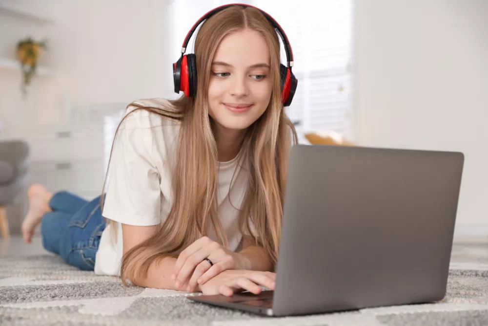 Nastolatka w słuchawkach przy laptopie podczas spotkania online