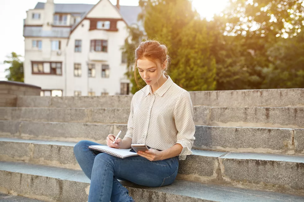 woman-writing-book-while-sitting-steps-campus