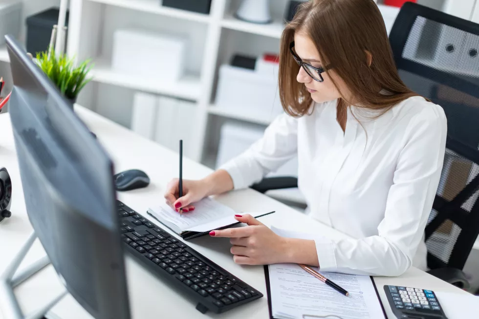 young-girl-sitting-table-working-with-computer-documents-calculator