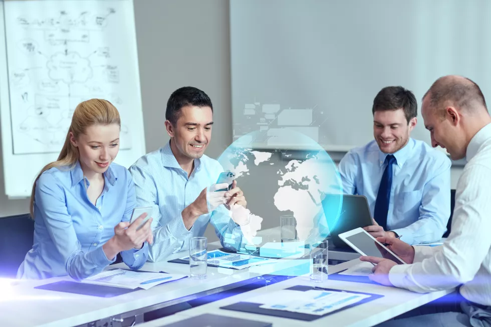 business-people-cooperation-technology-concept-smiling-business-team-with-gadgets-globe-hologram-meeting-office