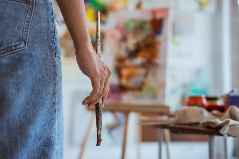 close-up-female-painters-hand-holding-paint-brush