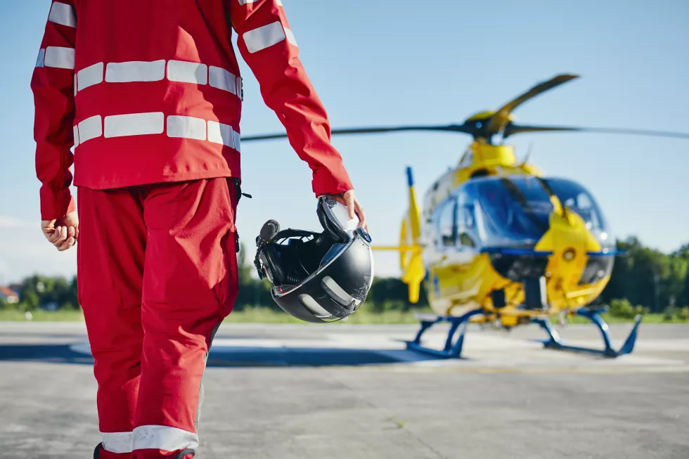 midsection-rescue-worker-holding-helmet-while-standing-near-helicopter-runway