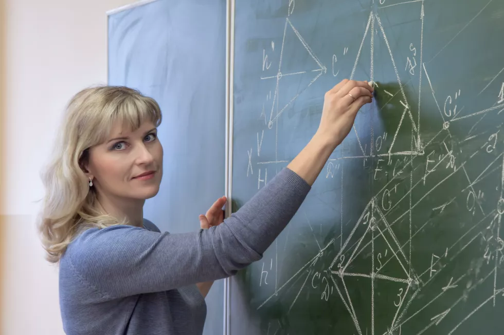portrait-woman-teaching-while-standing-by-blackboard-classroom