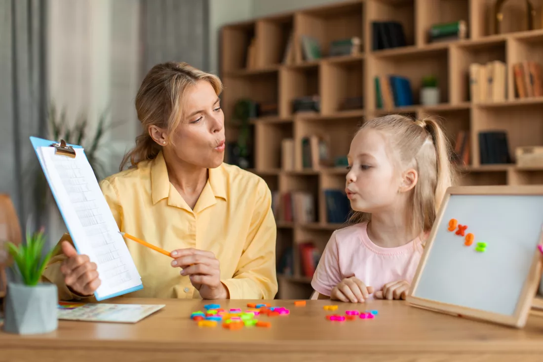 speech-training-kids-female-specialist-training-with-smart-little-girl-teaching-her-right-articulation-exercises(1)