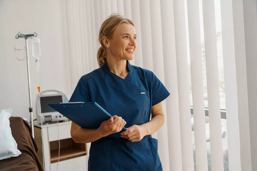 professional-nurse-with-tablet-standing-hospital-ward-looking-window